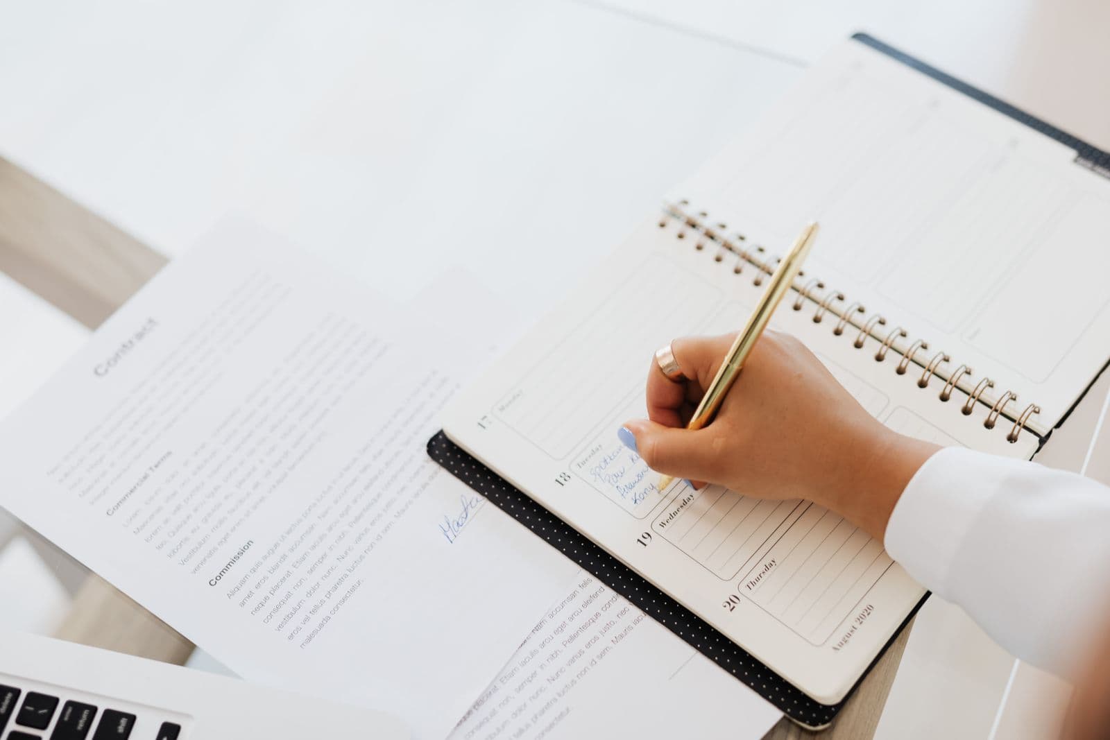 A clear diagnosis before you act on your SEO A hand writes an action plan in a notebook, next to a printed contract - SimplerWebs